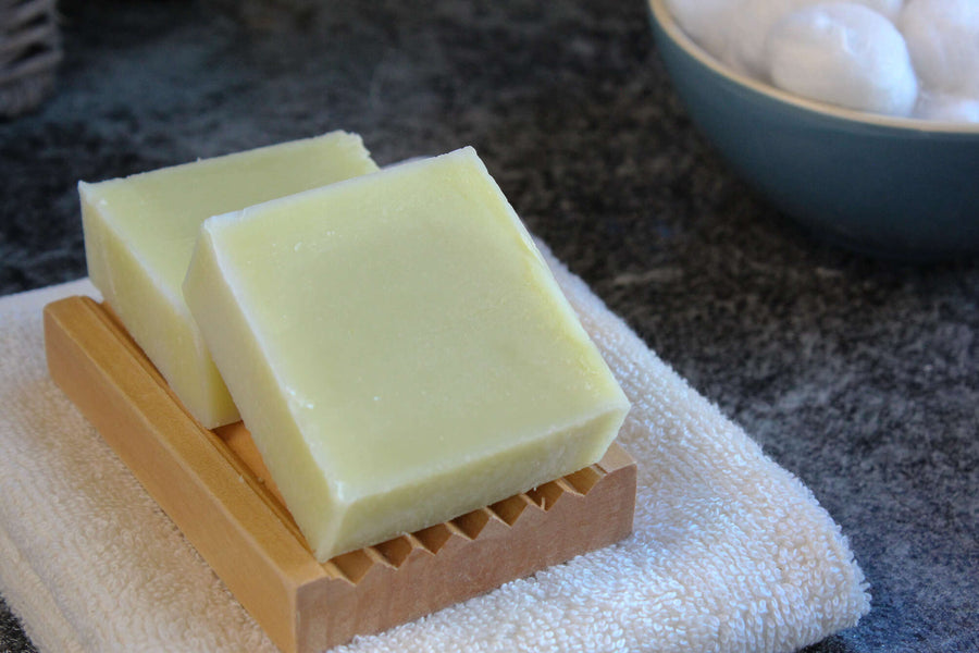 two unwrapped natural soap bars on a corrugated wooden soap dish